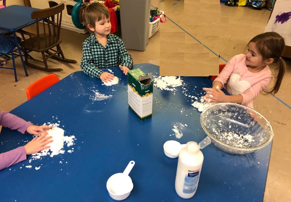 Children playing with white powder on a blue table