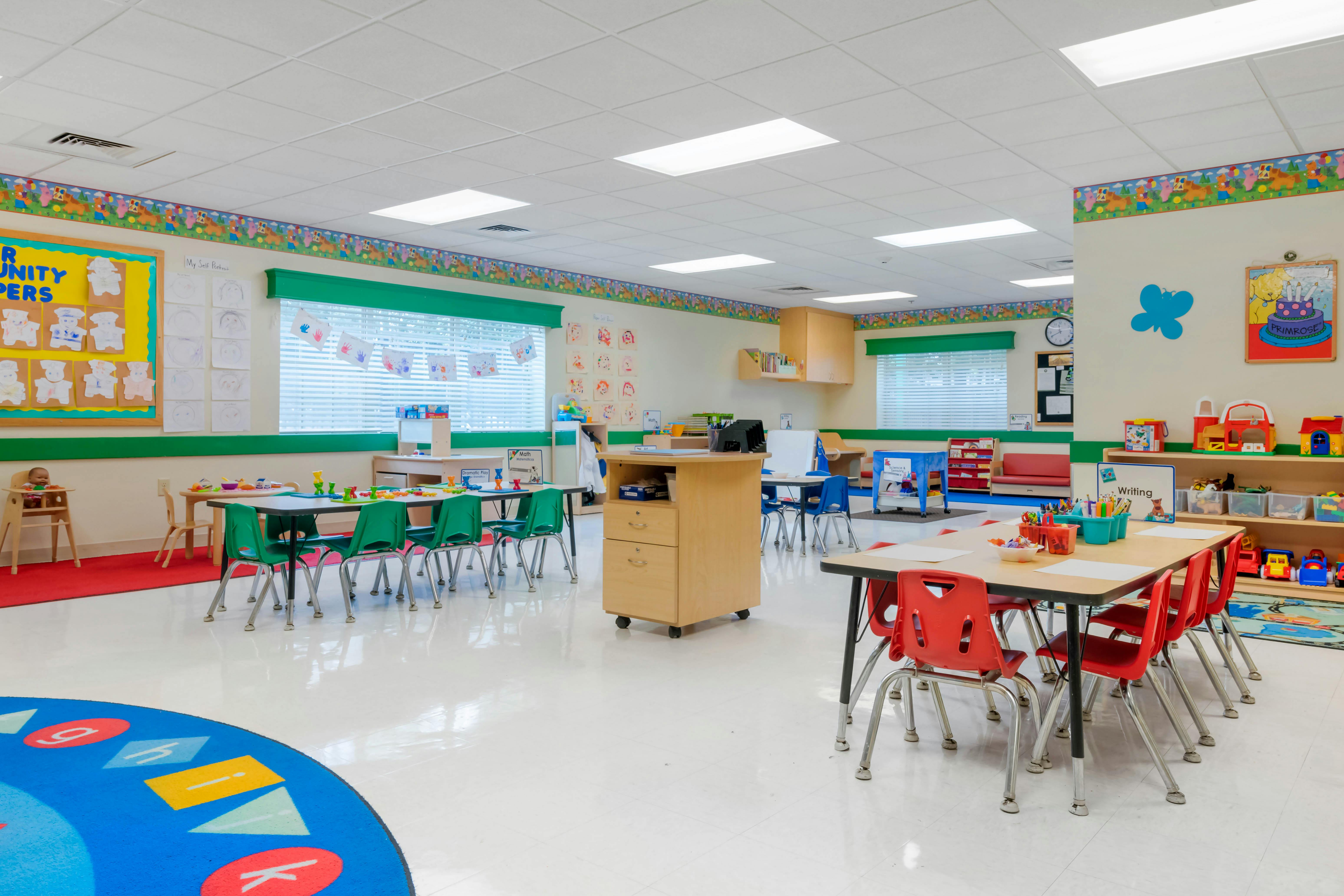 Empty classroom with small tables and chairs, colorful decorations on walls
