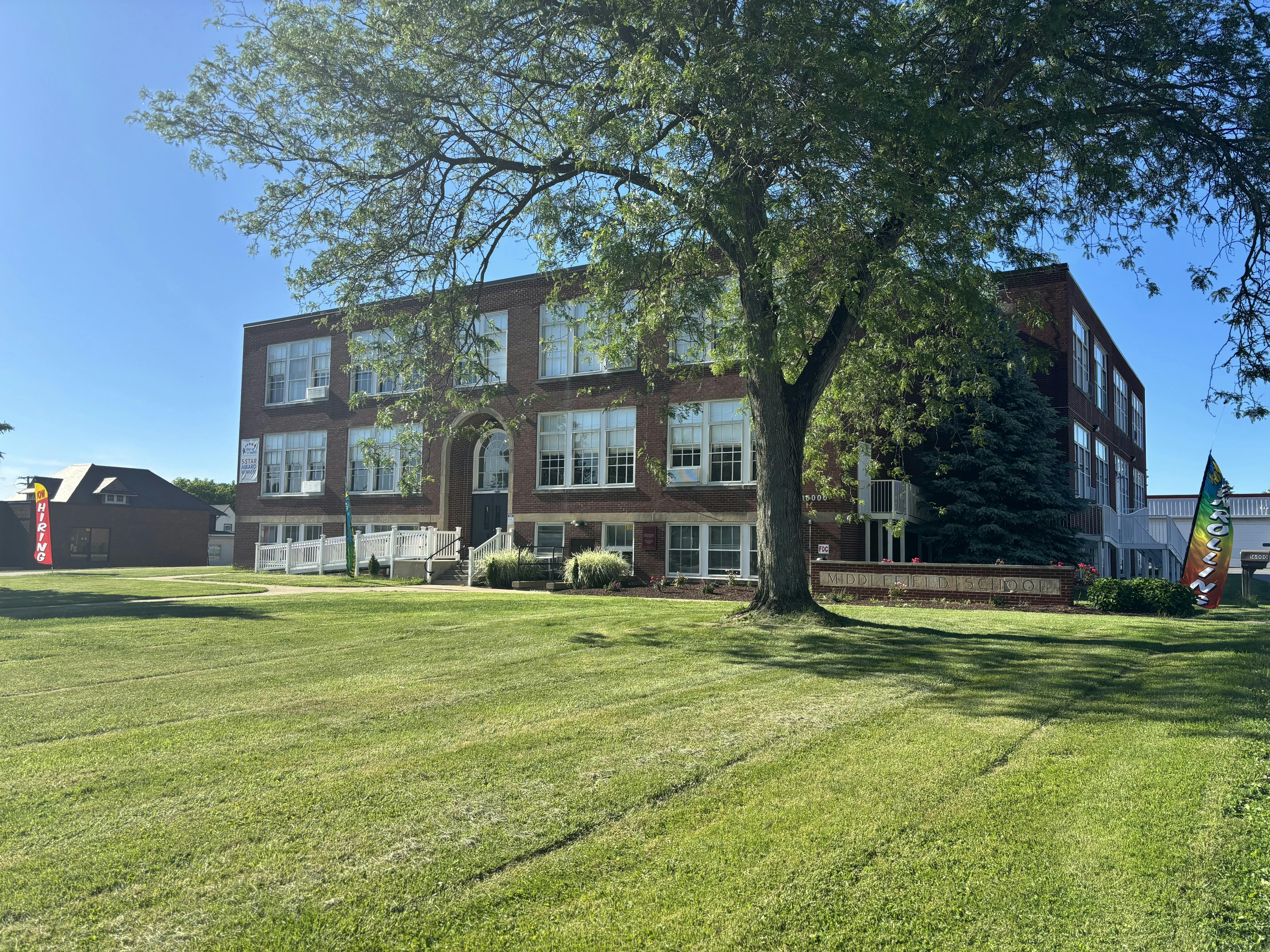 Large brick building with many windows and a green lawn in front