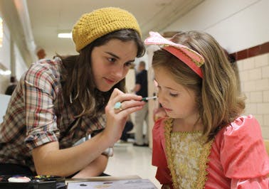 Person applying makeup to a child