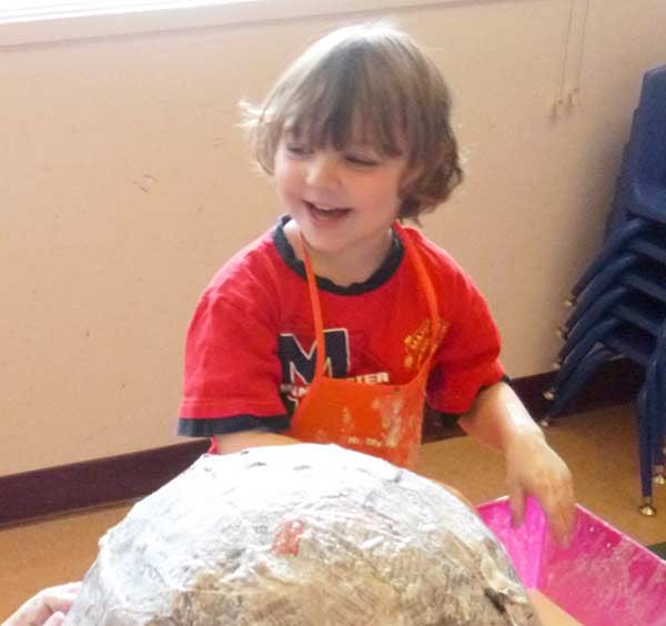 Child in an apron working on a craft project