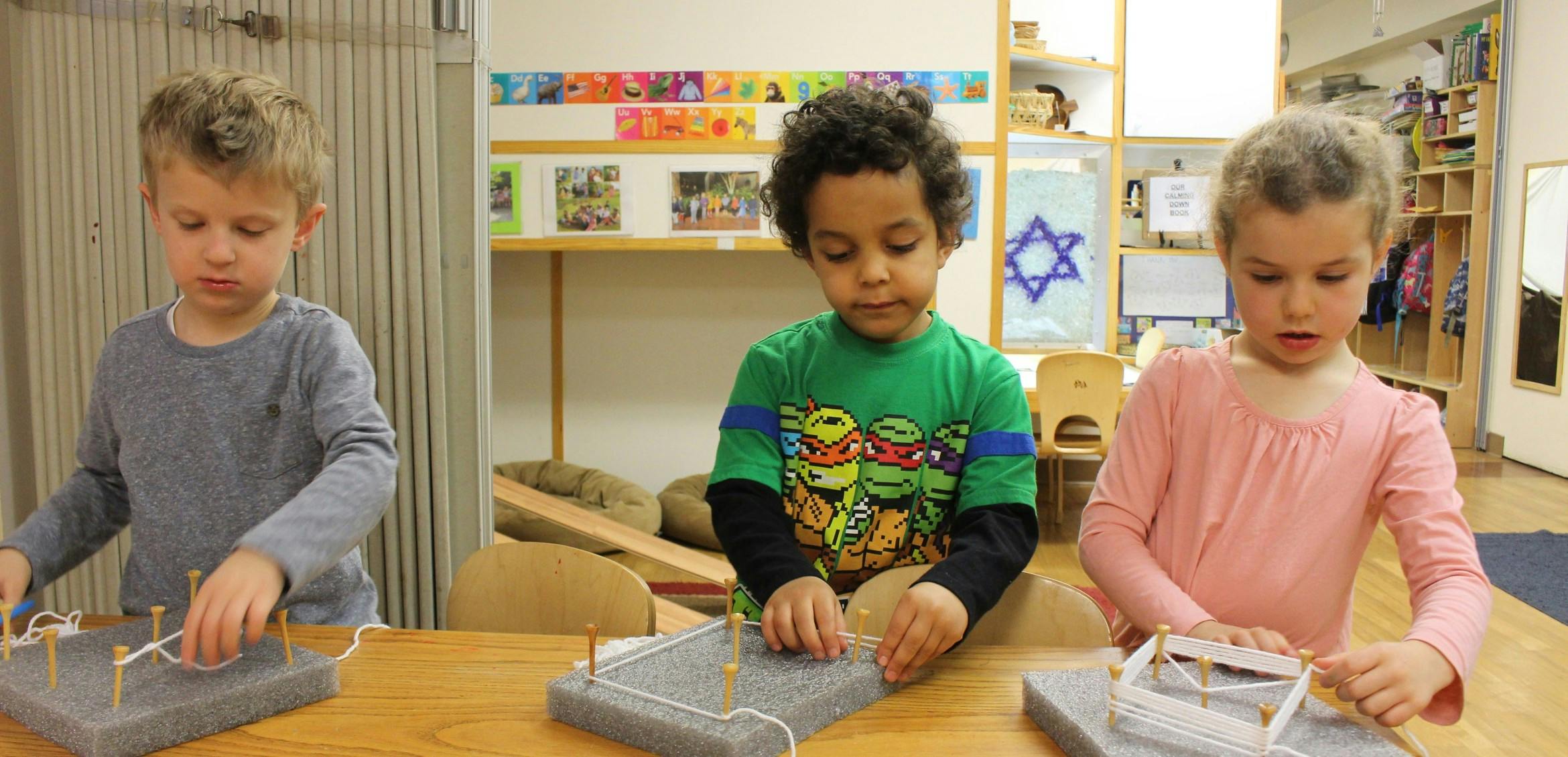 Three children working with building materials at a table
