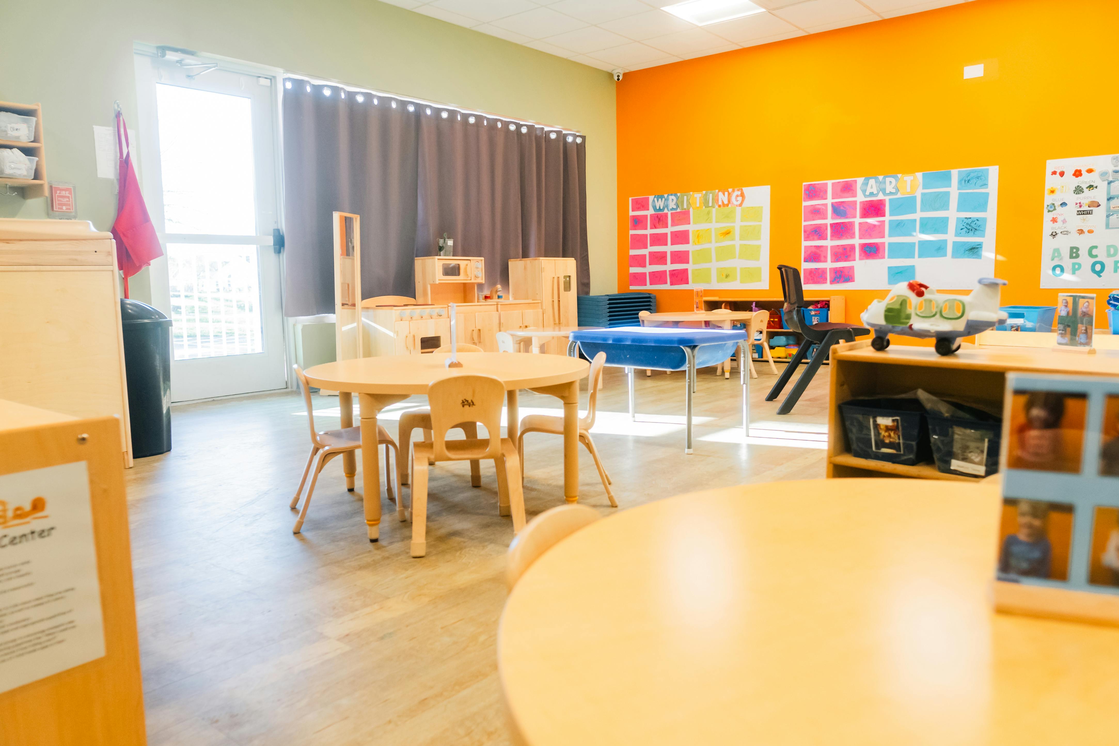 Classroom with child-sized tables and chairs, play kitchen, and colorful wall displays