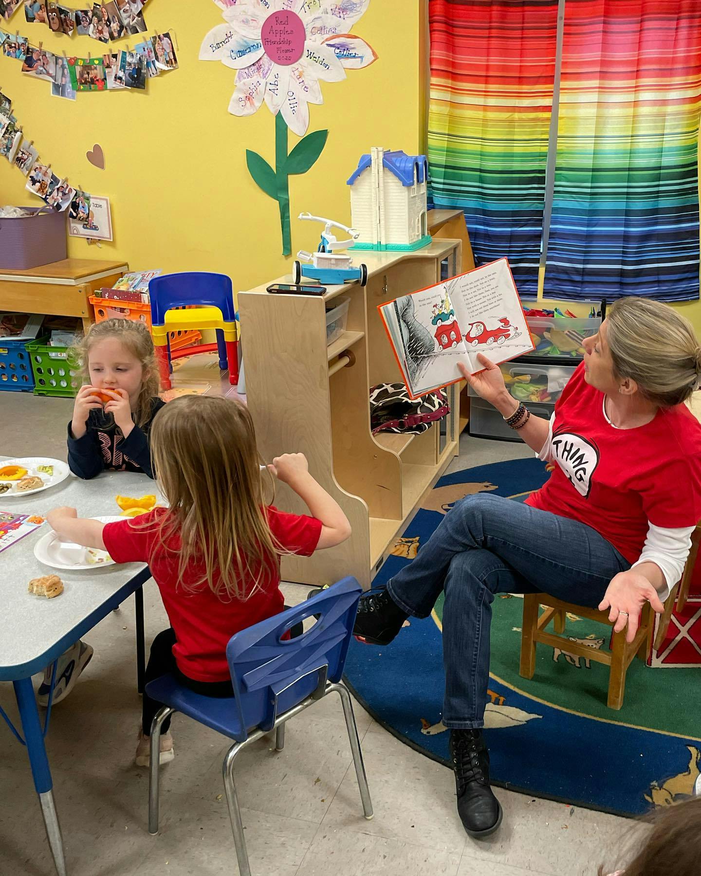 Person reading a book to two children in a classroom