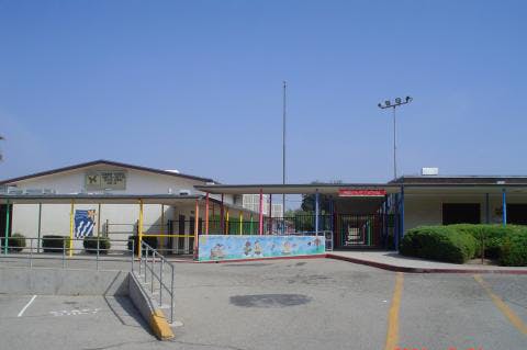 Exterior of a school building with a covered walkway and parking lot