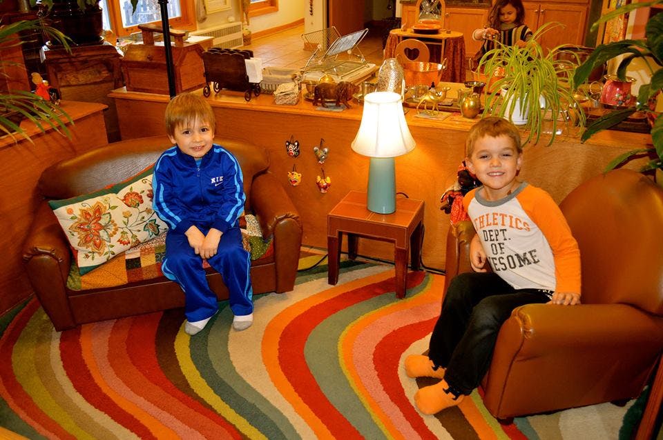 Two children sitting in armchairs on a colorful rug