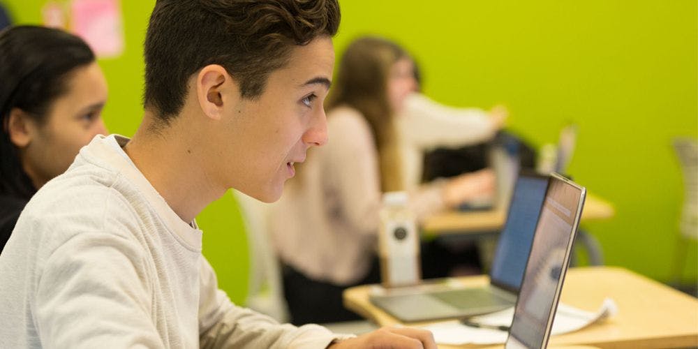Teen looking at laptop screen in a classroom