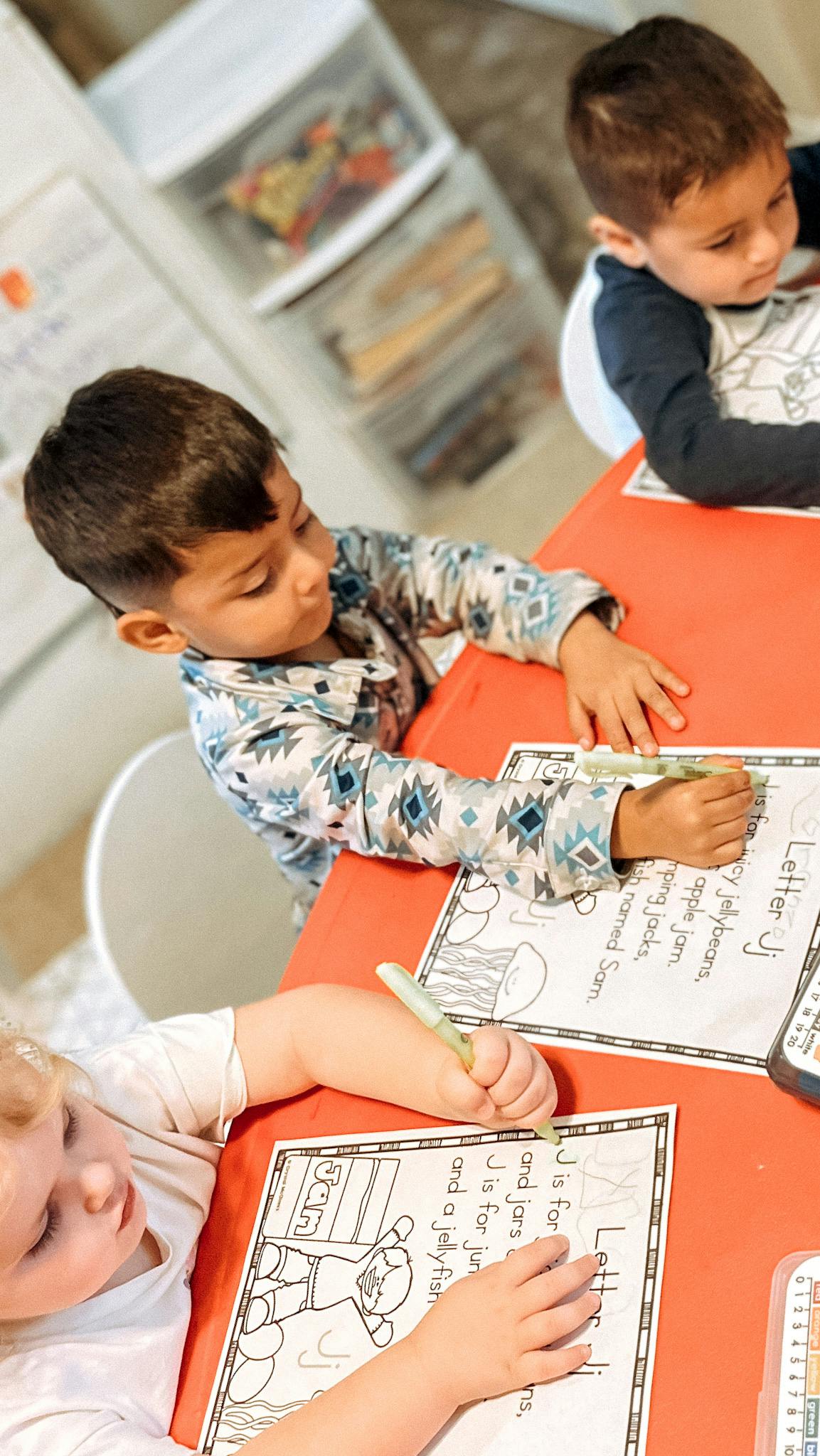 Three children writing on worksheets at a table