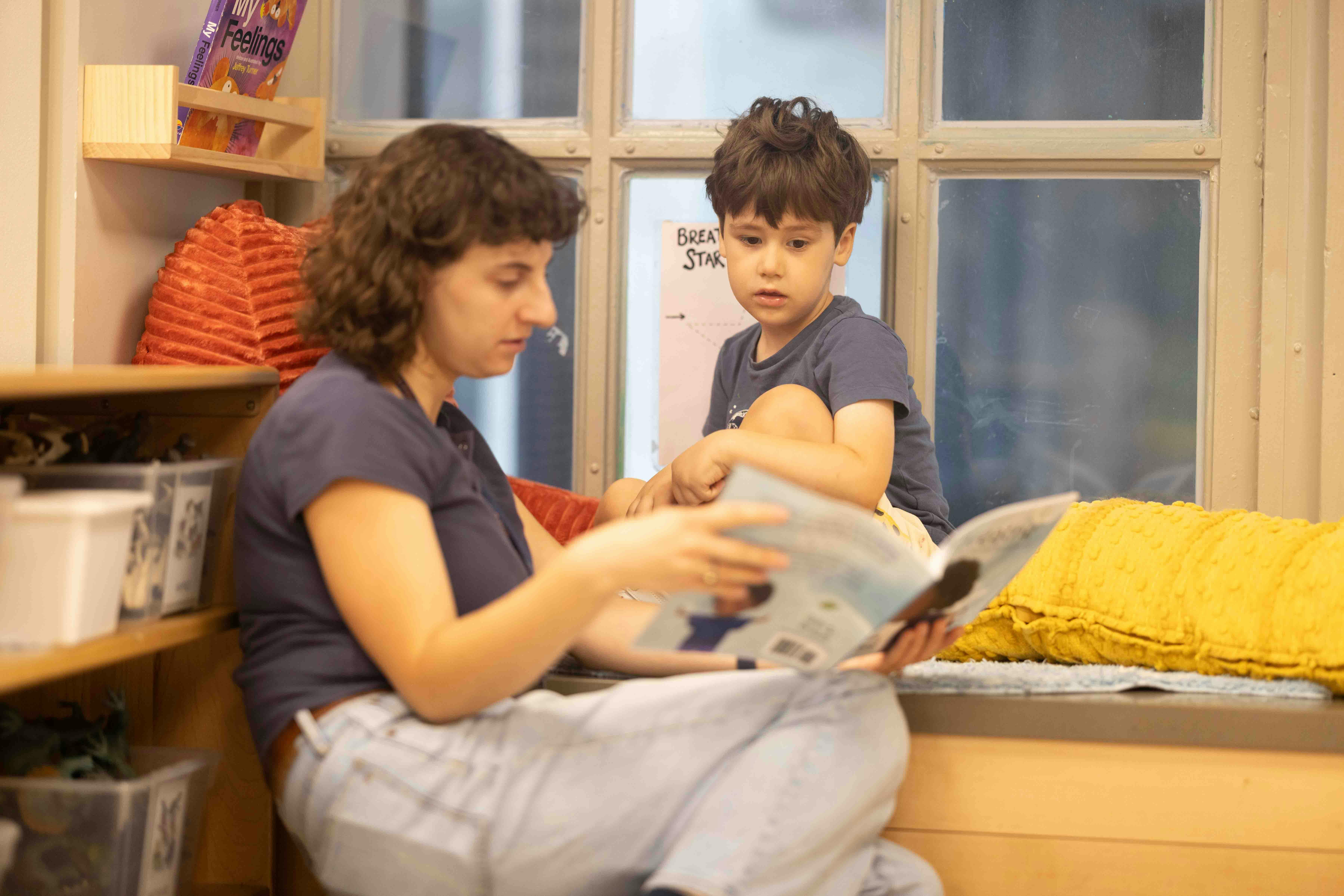Person reading a book to a child in a classroom