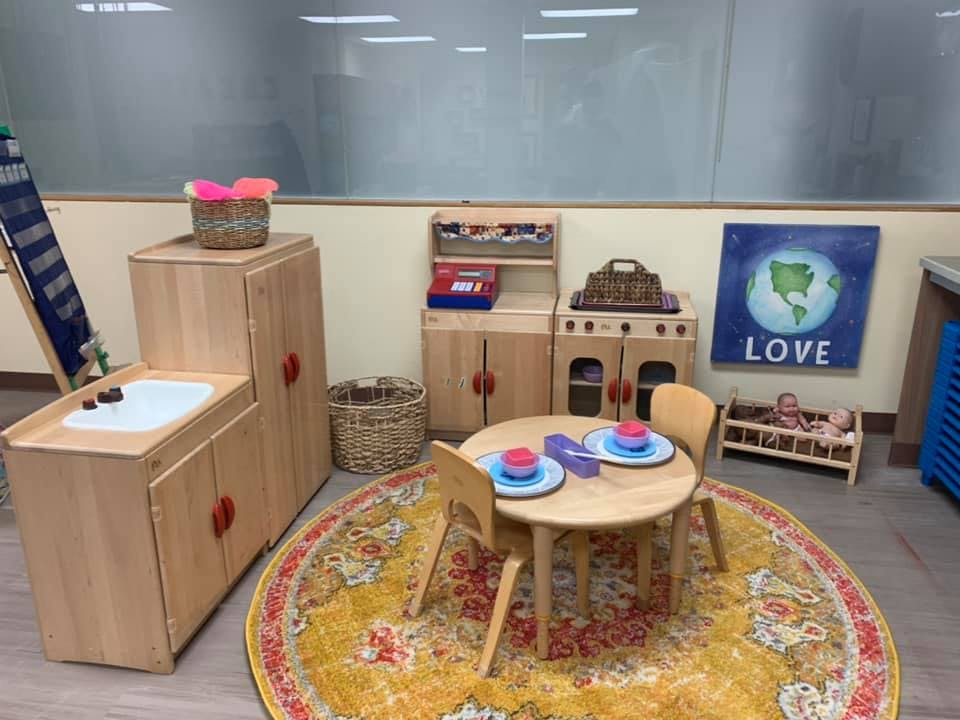 Play kitchen area with a small table and chairs on a rug