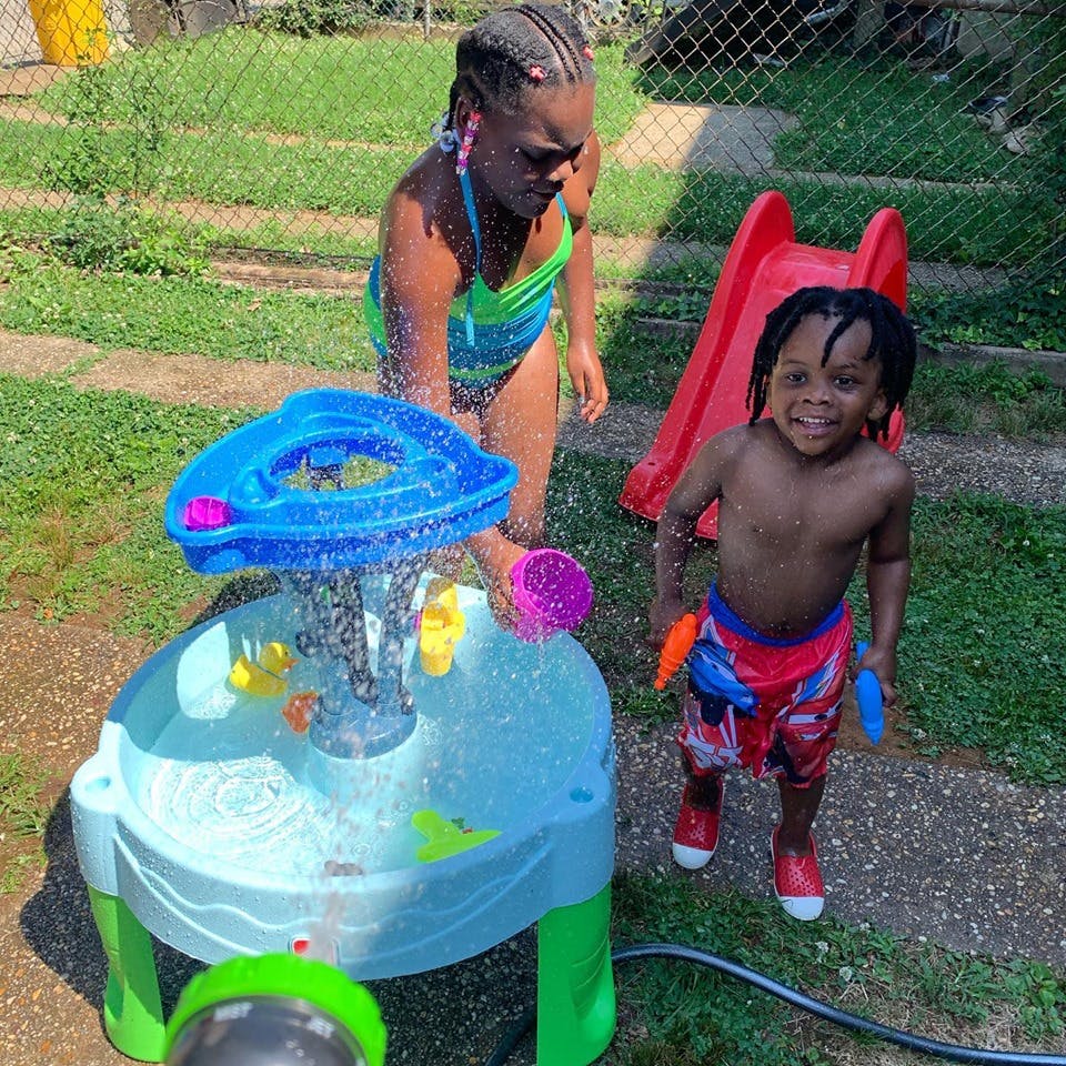 Person and child playing with a water table outdoors