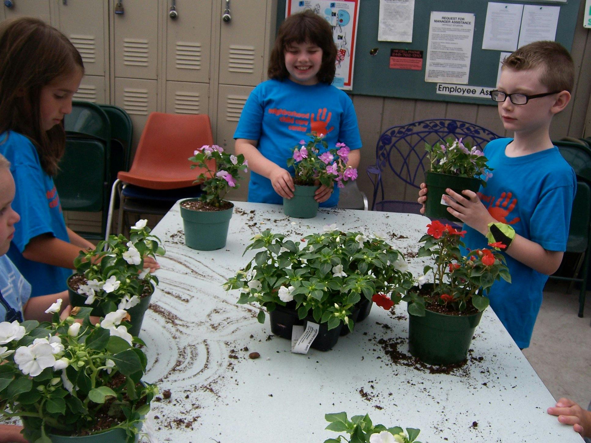 Children planting flowers at a table