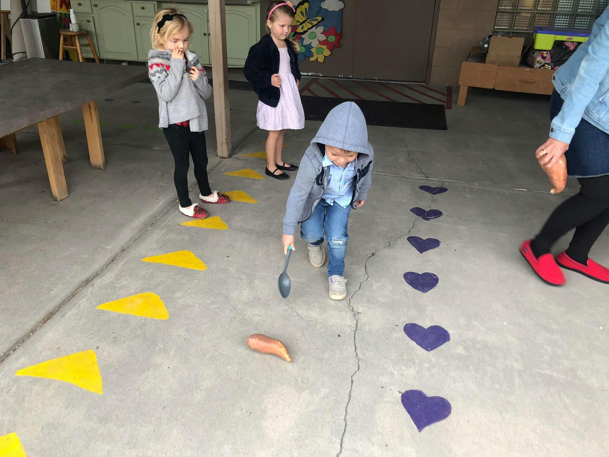 Child playing with a spoon and sweet potato on a path of hearts