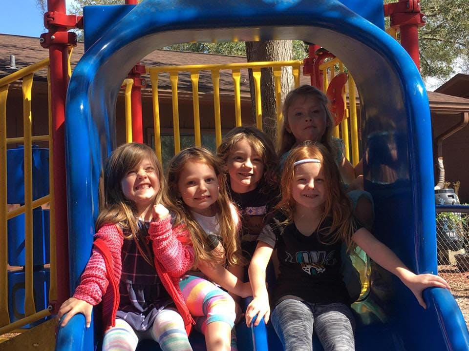 Five children on a blue playground slide