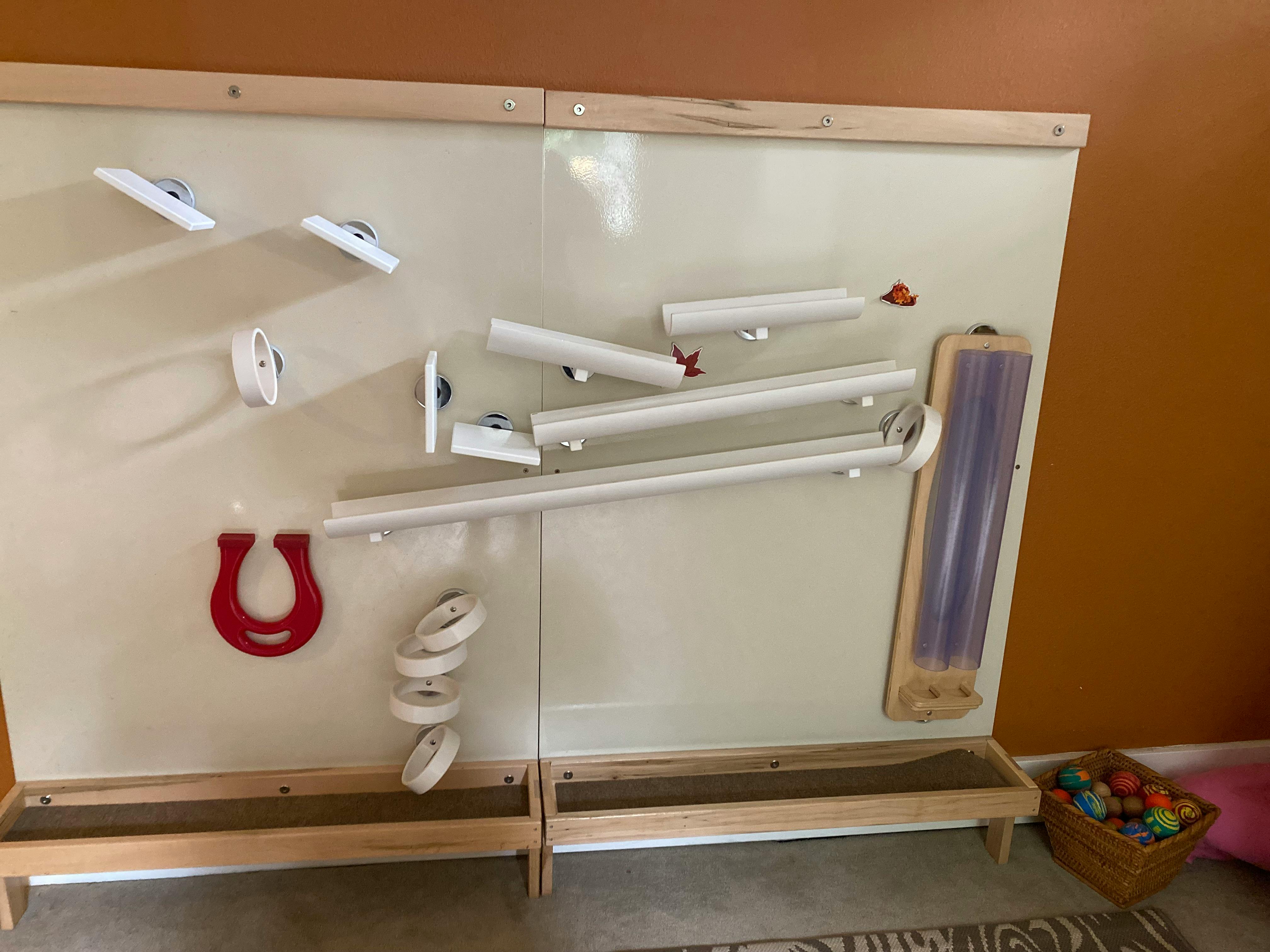 Wall-mounted ball run with tubes, ramps, and a red horseshoe magnet