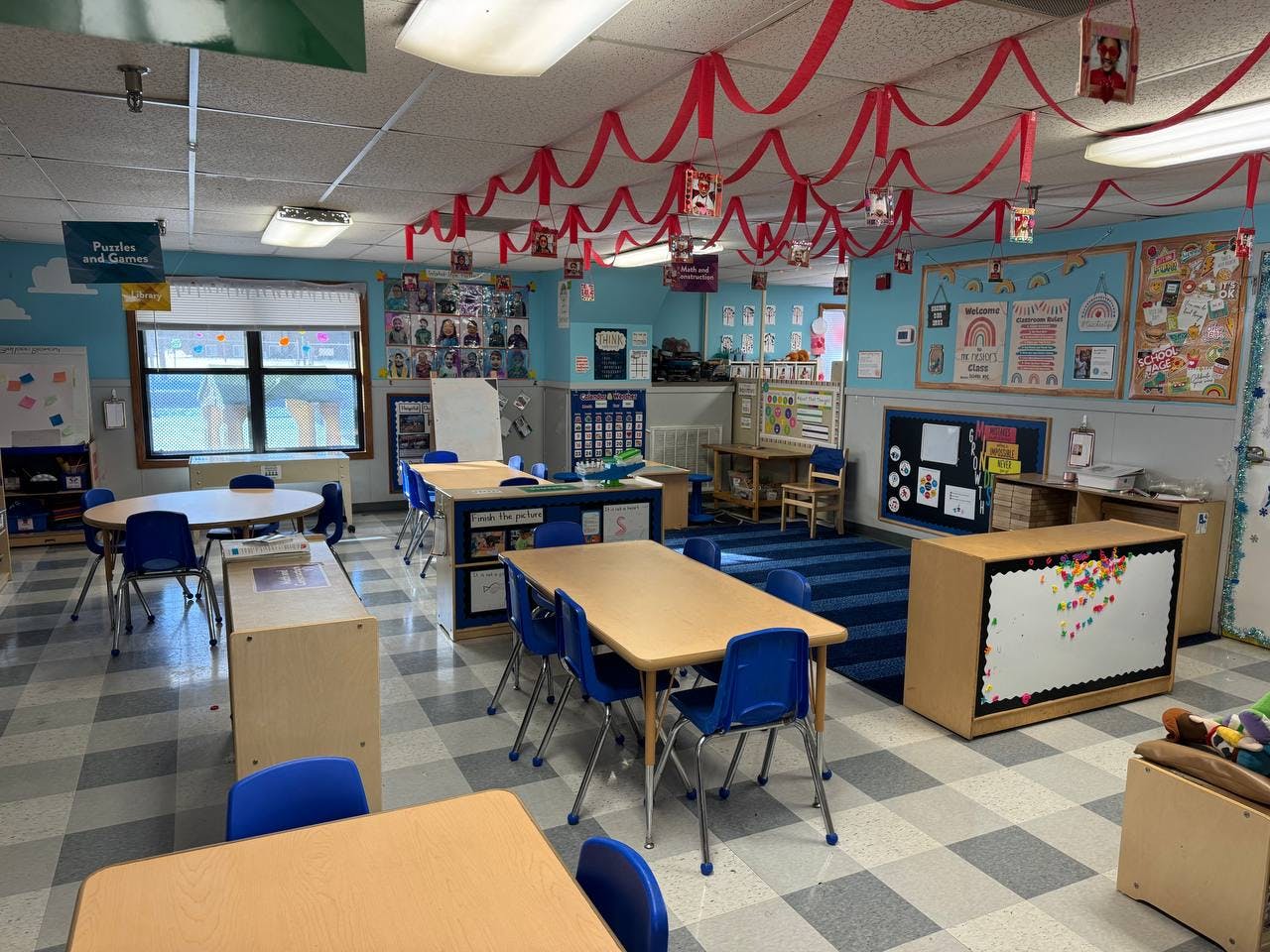 Empty classroom with small tables and chairs, decorated ceiling