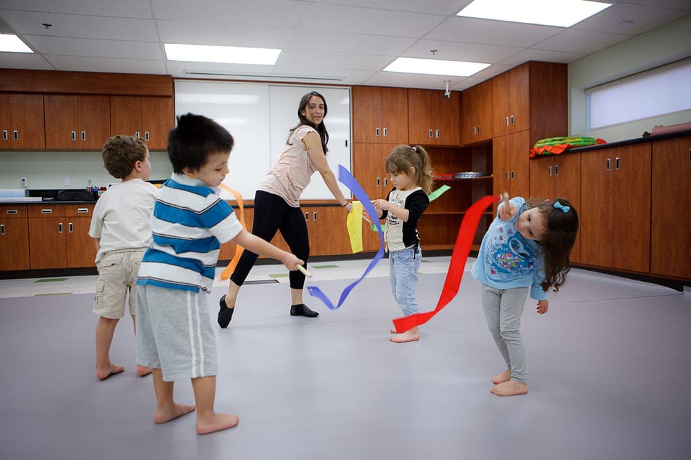 Adult and children playing with colorful ribbons in a room