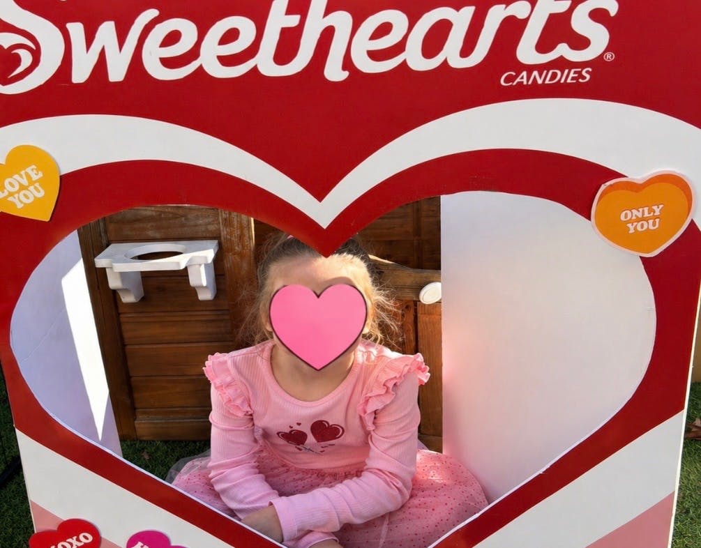 Child sitting inside a heart-shaped Sweethearts Candies cutout