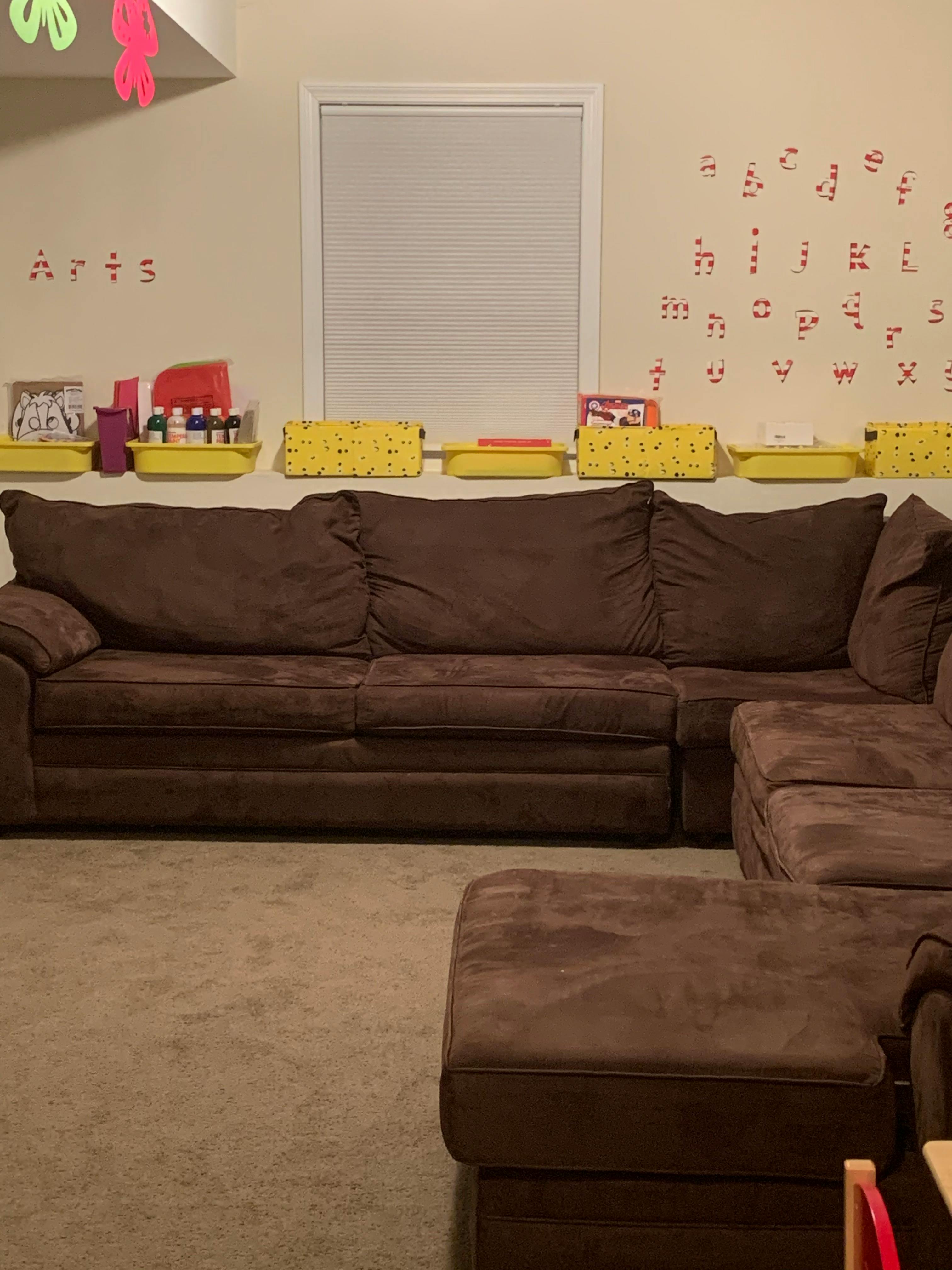 Brown sectional sofa with yellow bins on a shelf above
