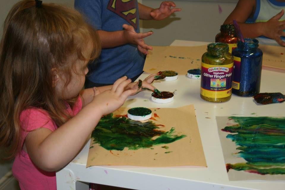 Child painting with green paint on paper