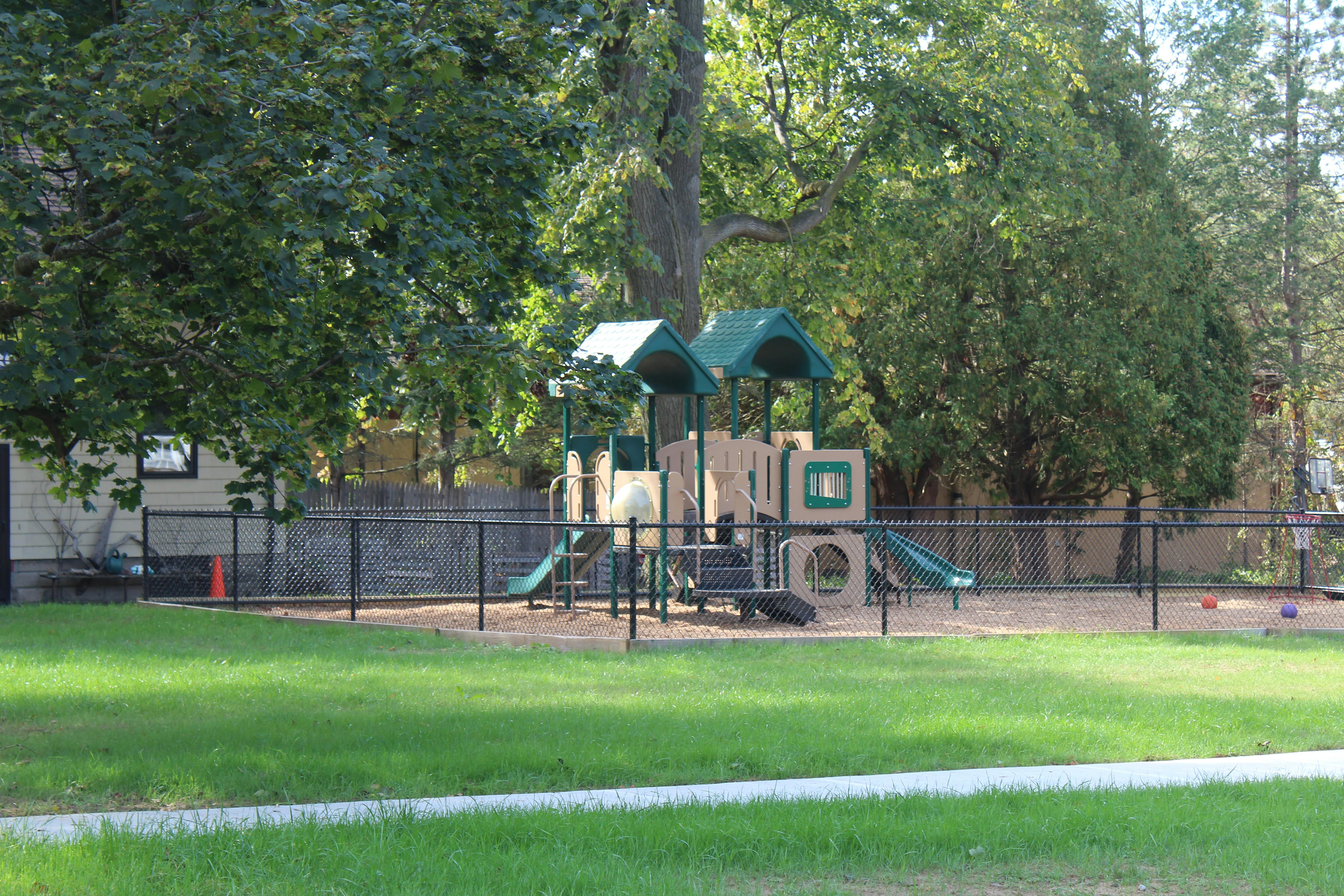 Playground with slides and climbing structures behind a fence