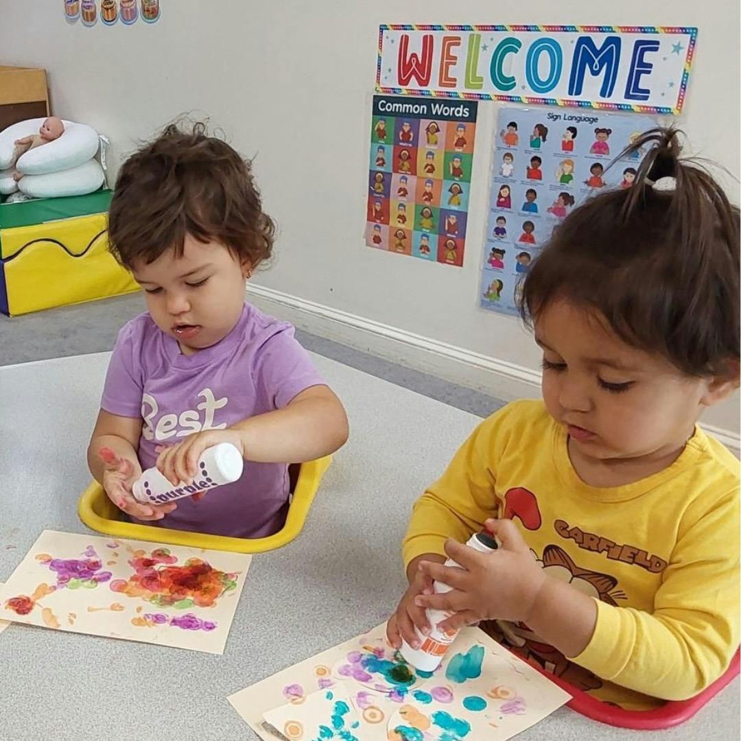 Two children painting with dot markers in a classroom