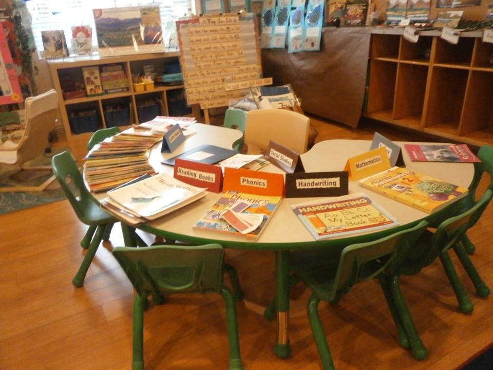 Classroom table with books and green chairs