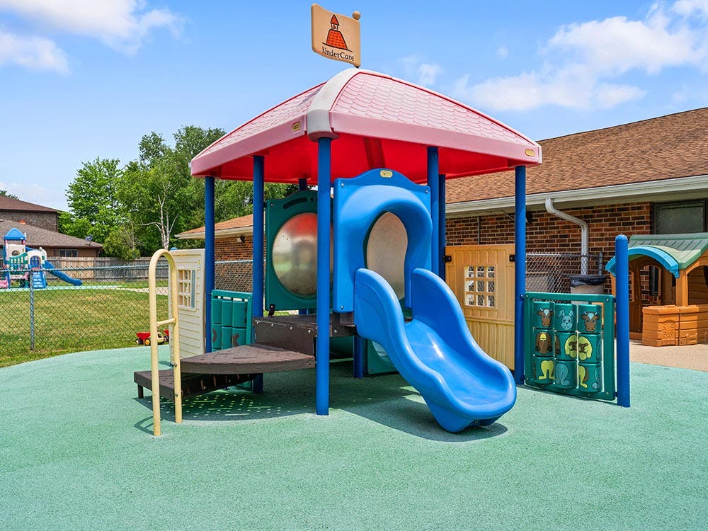 Colorful playground with slide and small houses on a green padded ground