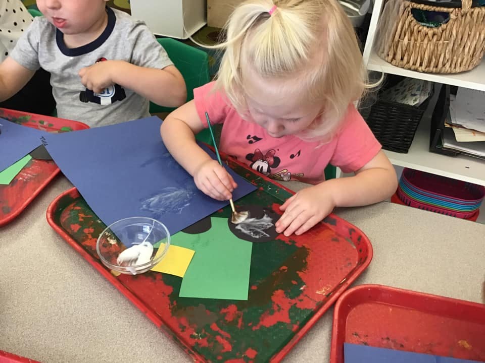 Child painting on paper at a table