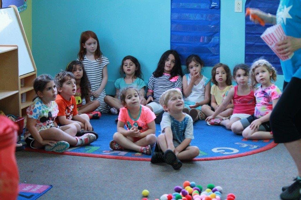 Group of children sitting on the floor looking at a person holding a popcorn box