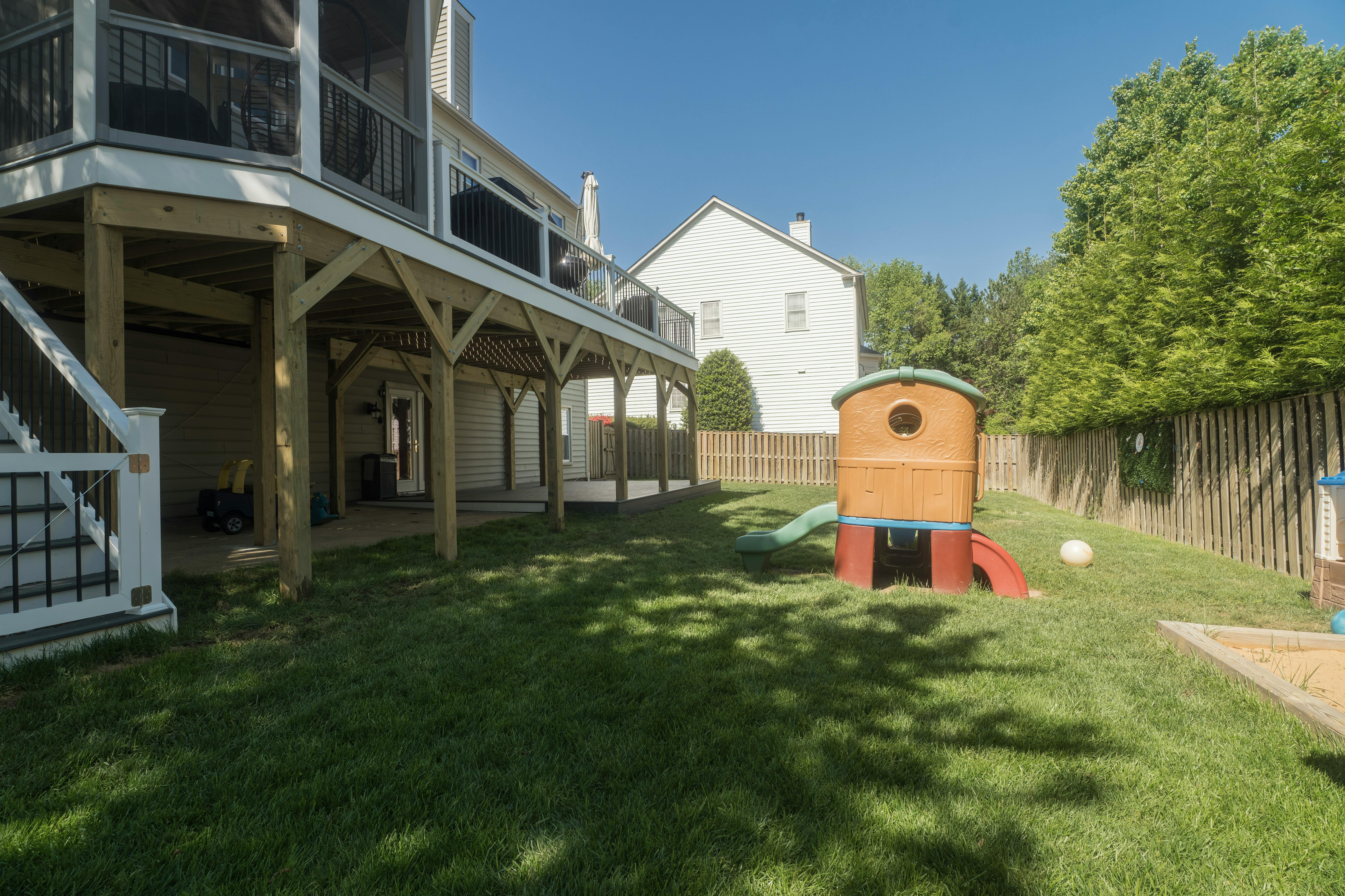 Backyard with a raised wooden deck and a child's playhouse with a slide