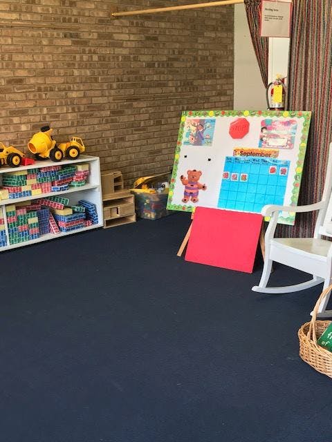 Classroom with toys, a calendar board, and a white rocking chair