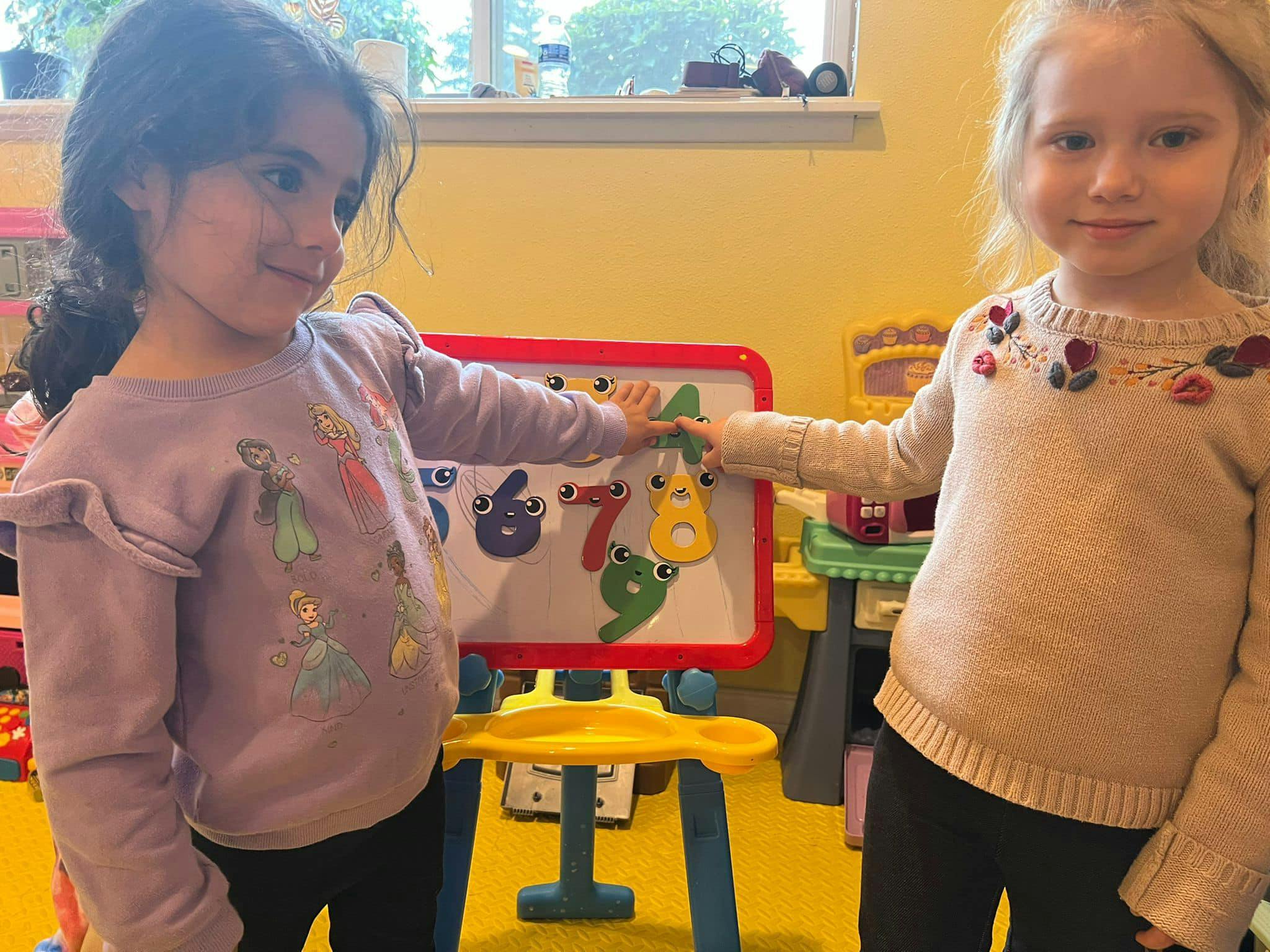 Two children playing with a number puzzle board