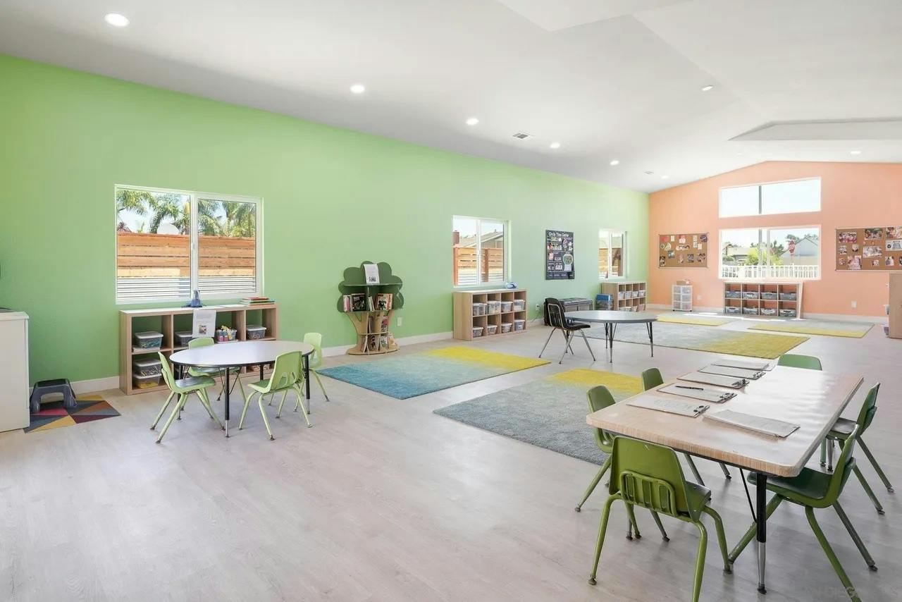 Spacious classroom interior with tables, chairs, and rugs
