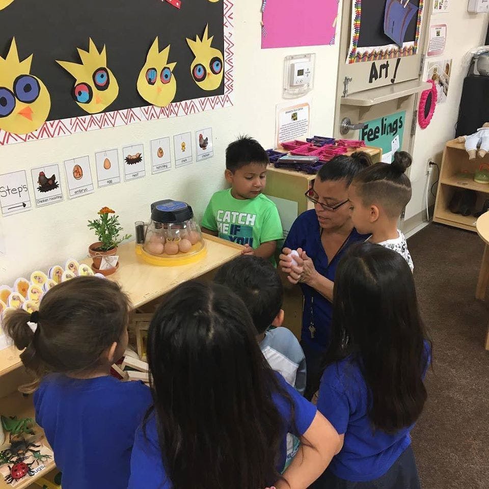 Adult and children gathered around a table in a classroom