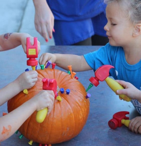 Children hammering pegs into a pumpkin