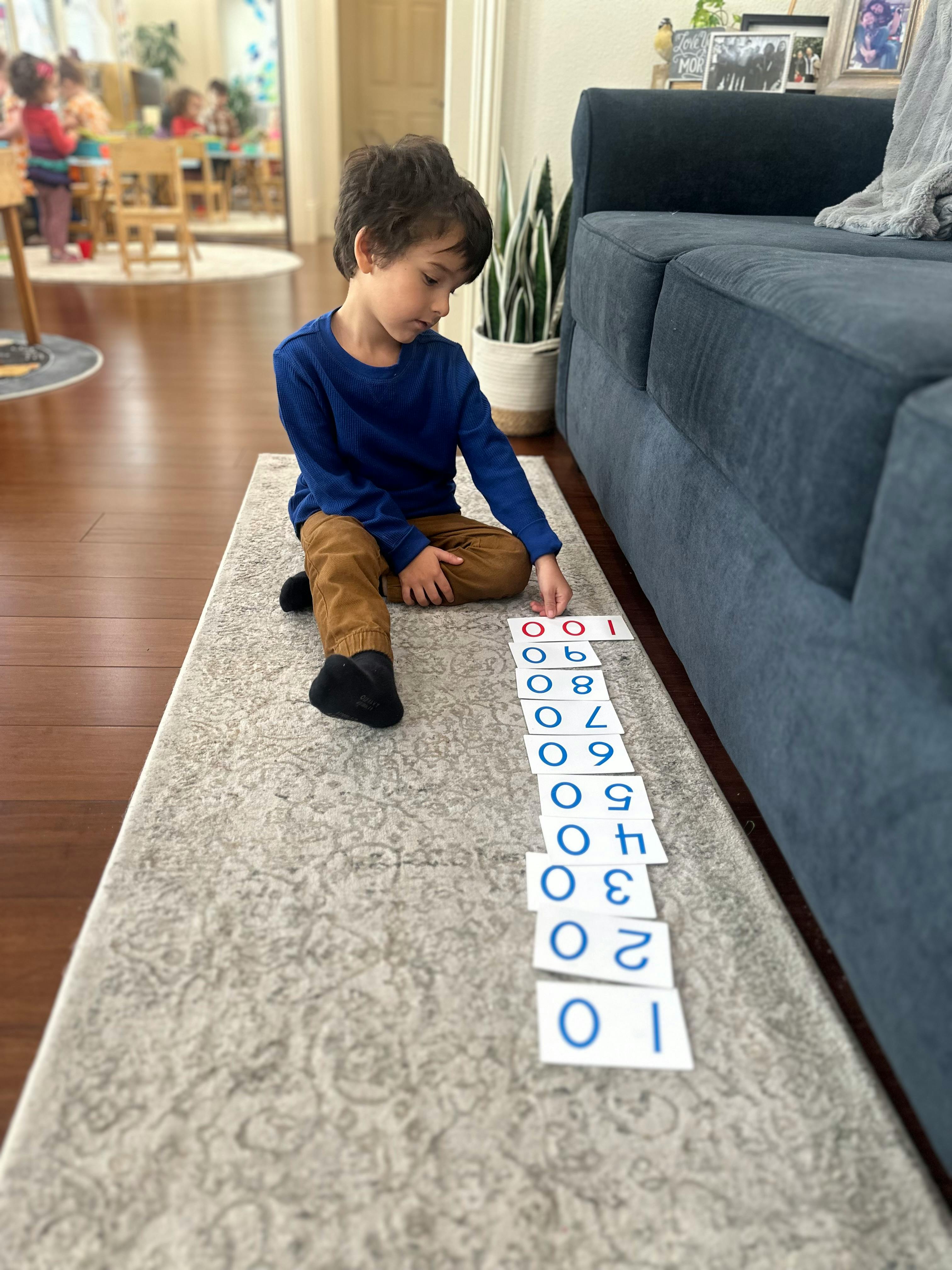 Child sitting on a rug arranging number cards in a line