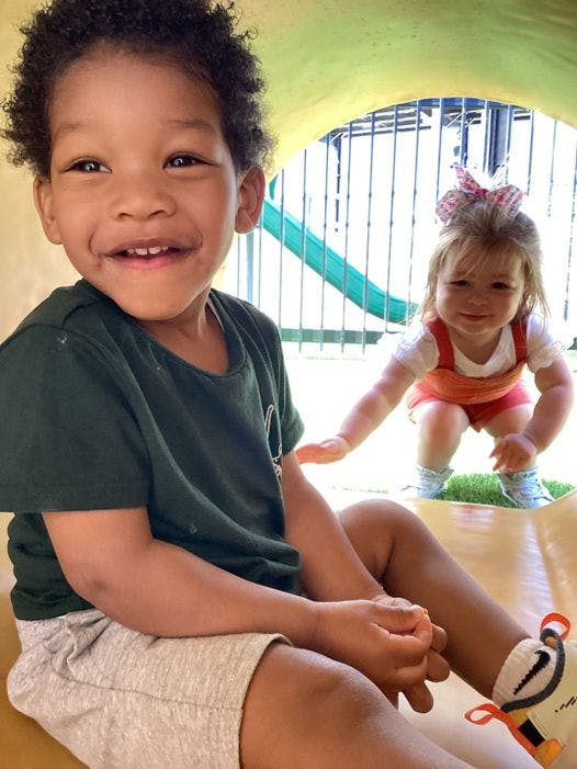 Child sitting in a tunnel with another child in the background