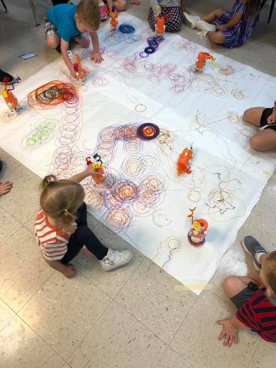 Children drawing on a large sheet of paper on the floor