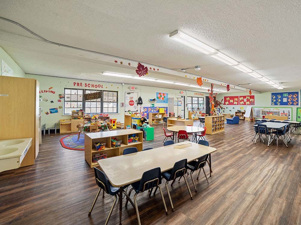An empty preschool classroom with small tables and chairs