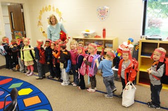Adult and children standing in a line in a classroom