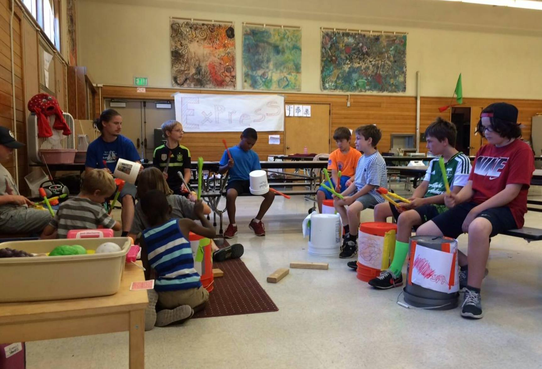 Children and teens playing drums made from buckets