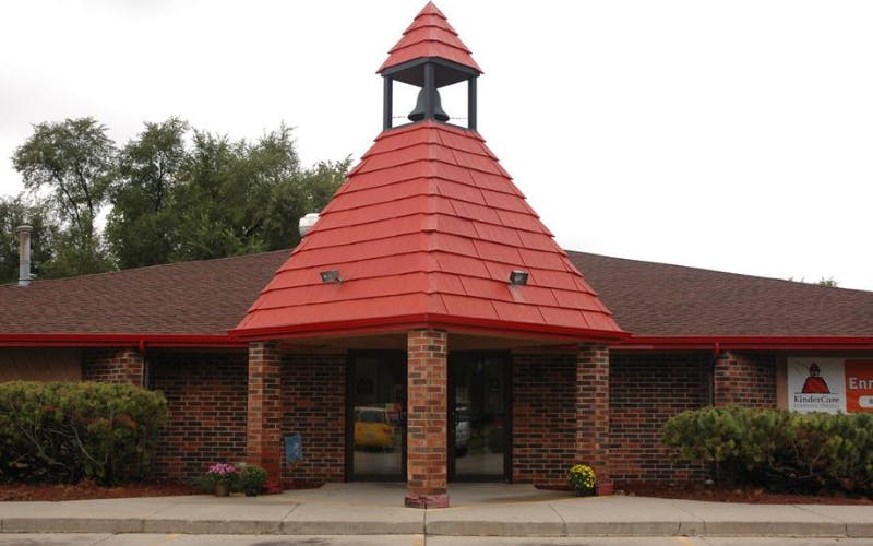 Brick building entrance with a red roof and a bell tower