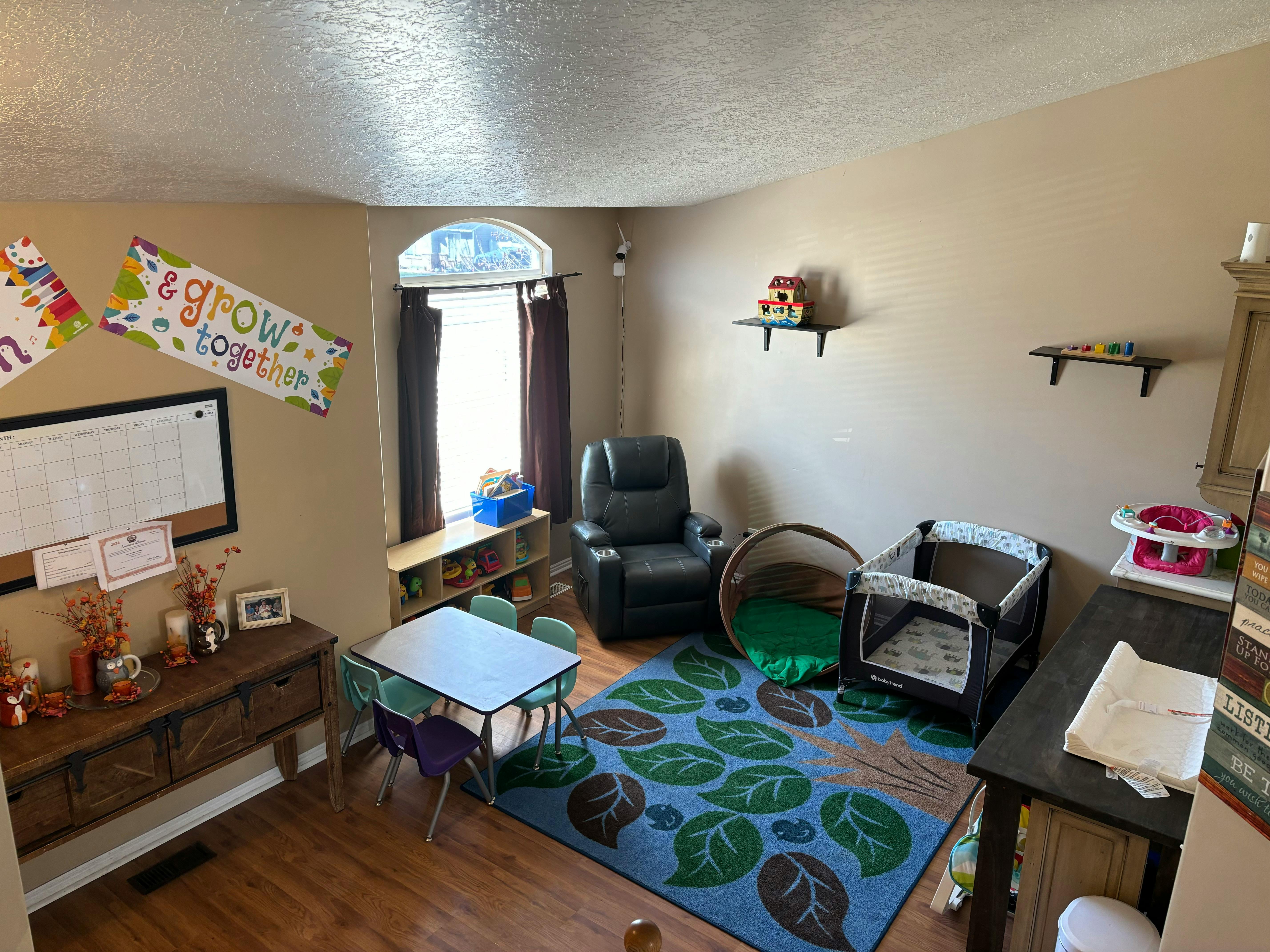 Room with a small table and chairs, a recliner, and a playpen