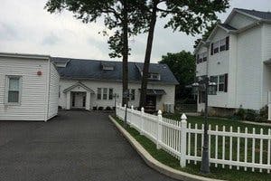Driveway leading to a building with a white picket fence