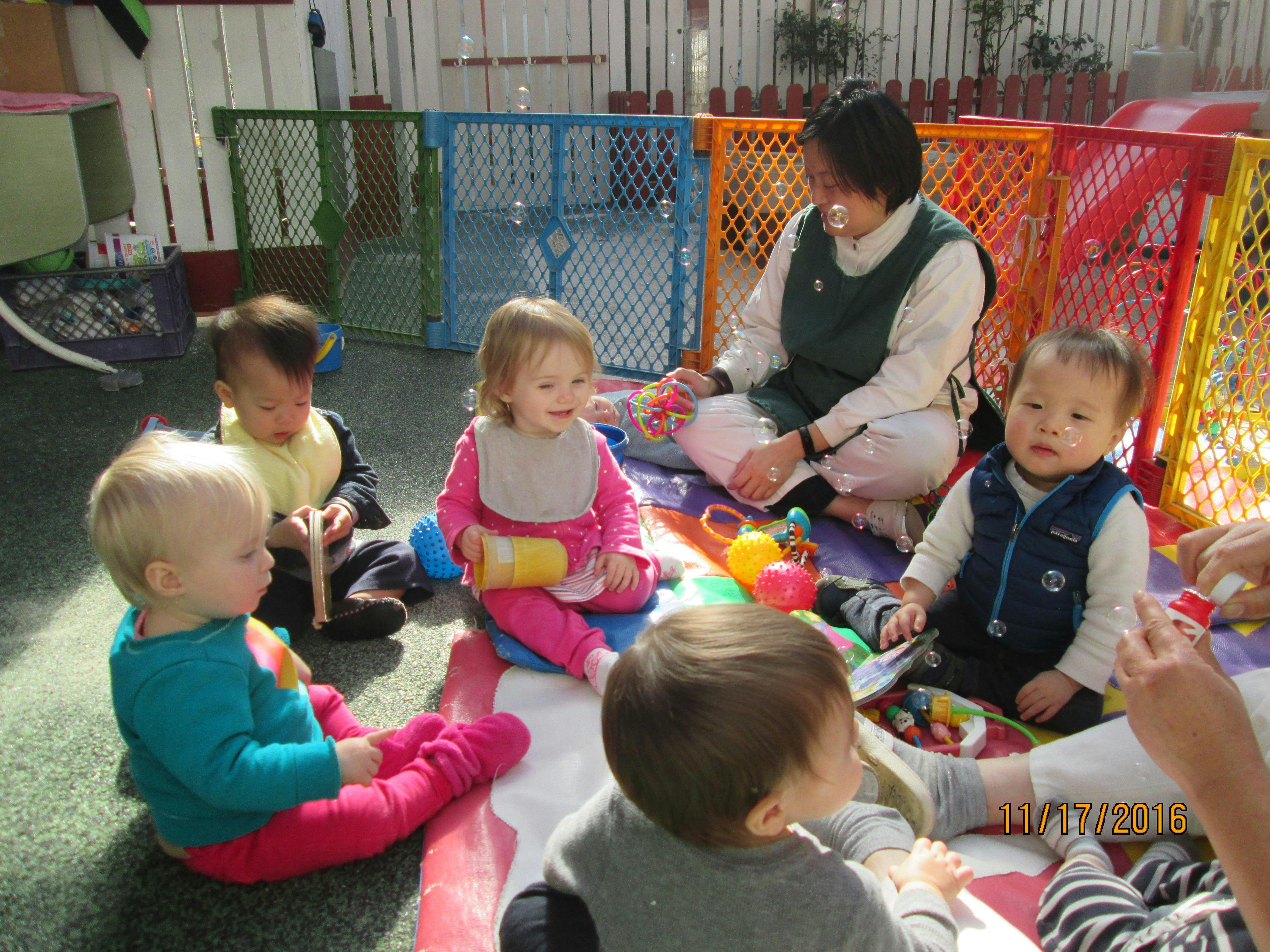 Person sitting with multiple children on a colorful mat