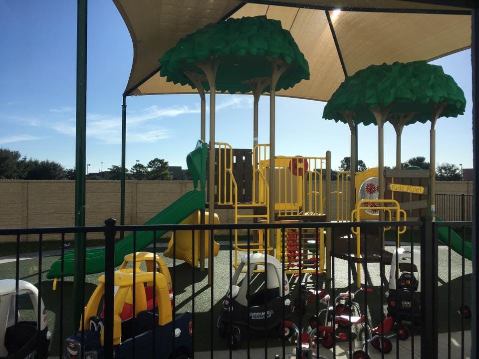 Playground with slides, climbing structures, and ride-on toys under a shade