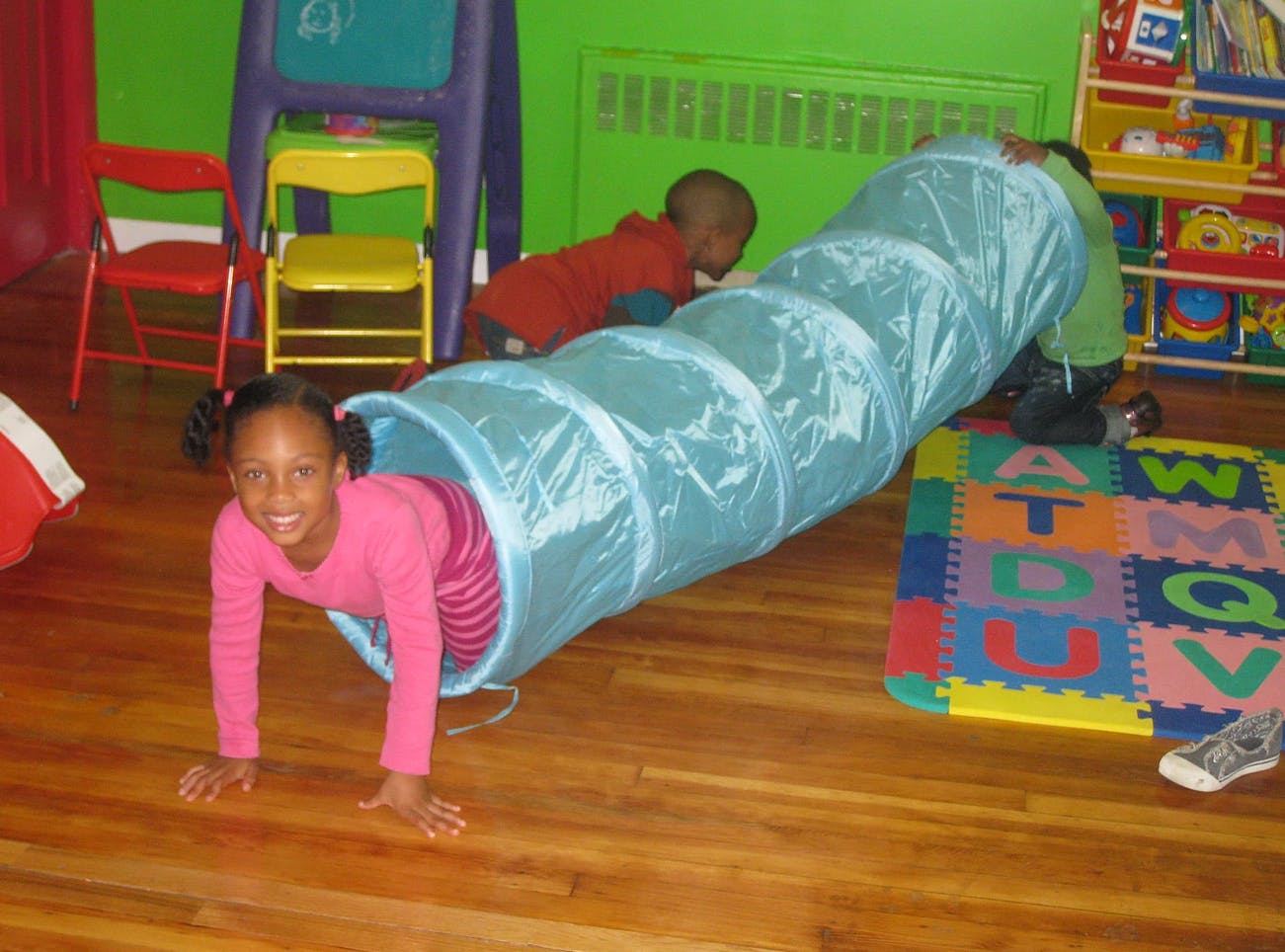 Child crawling out of a play tunnel, another child in the background