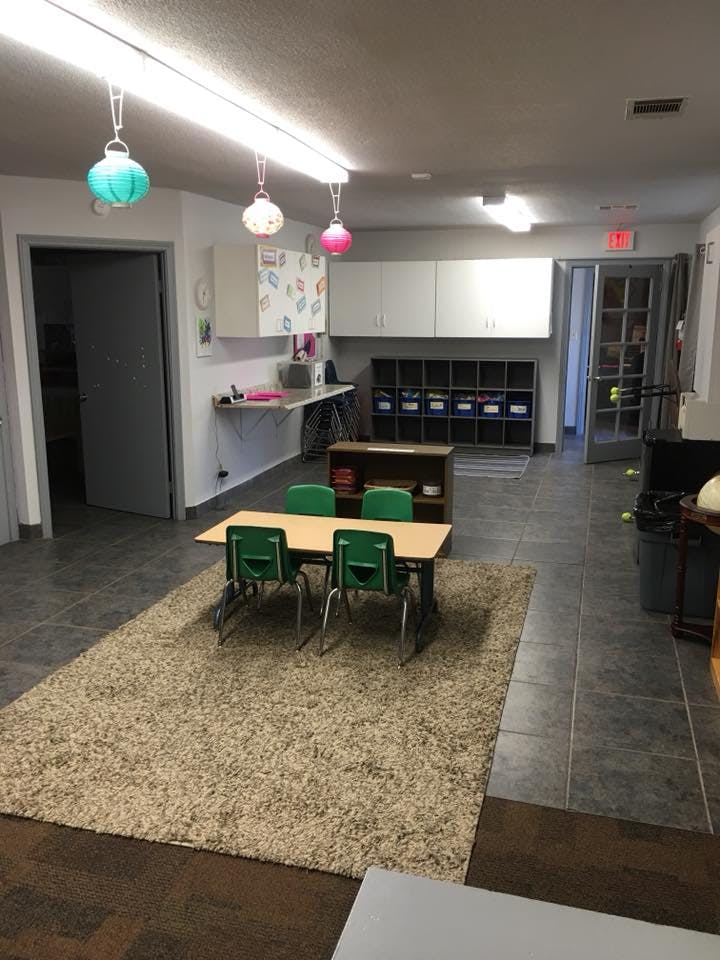 Classroom with small table and green chairs on a rug