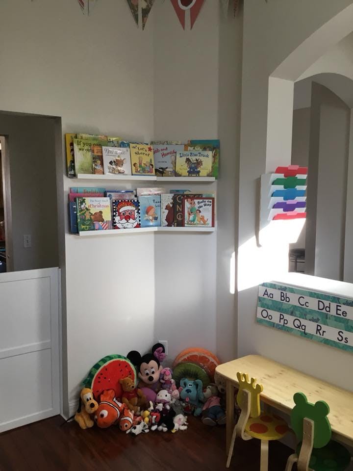 Children's books on shelves above stuffed animals and a small table with chairs